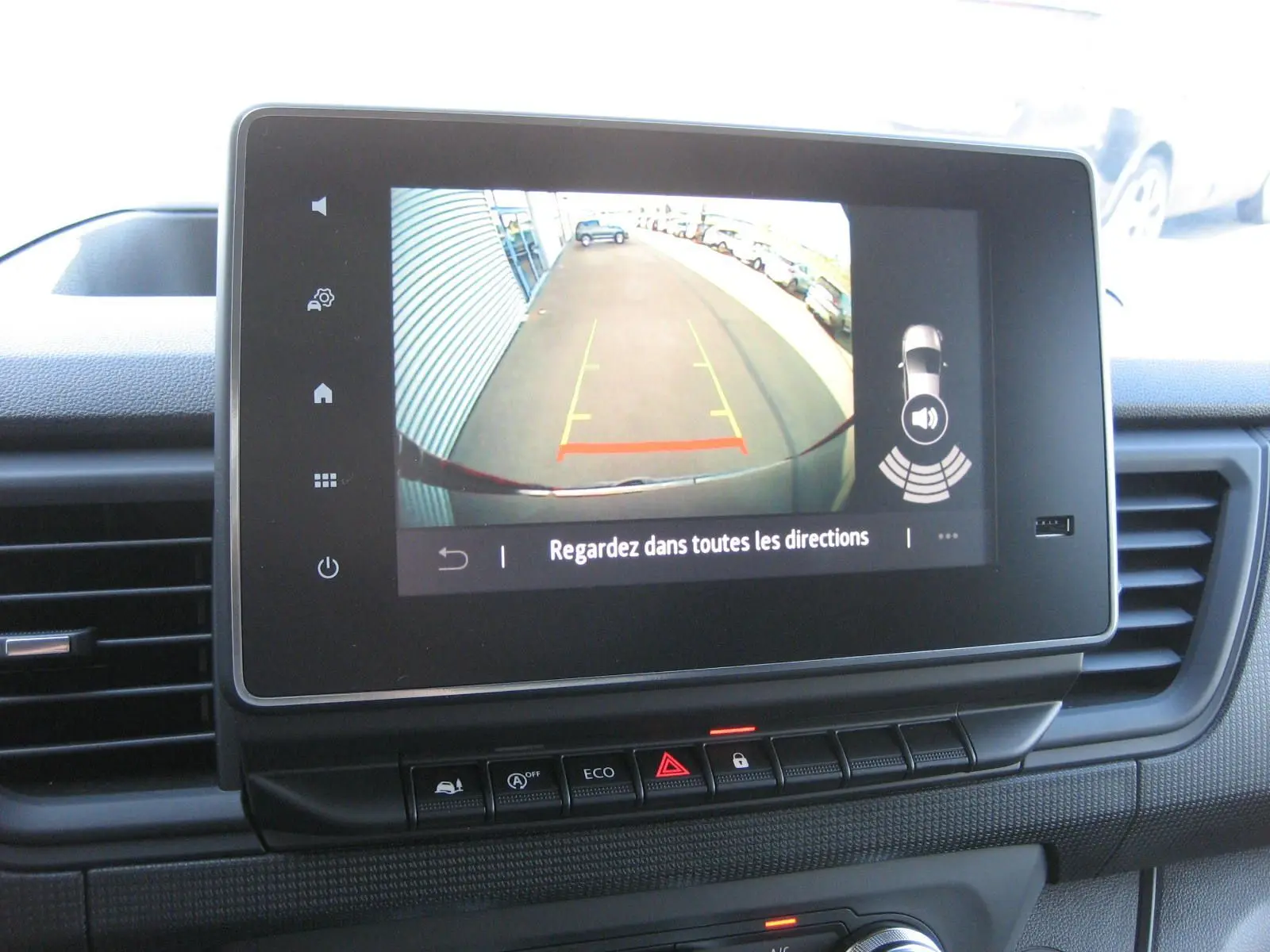 Écran central du Renault Trafic Fourgon gris comète montrant la caméra de recul avec lignes de guidage et alertes sonores.