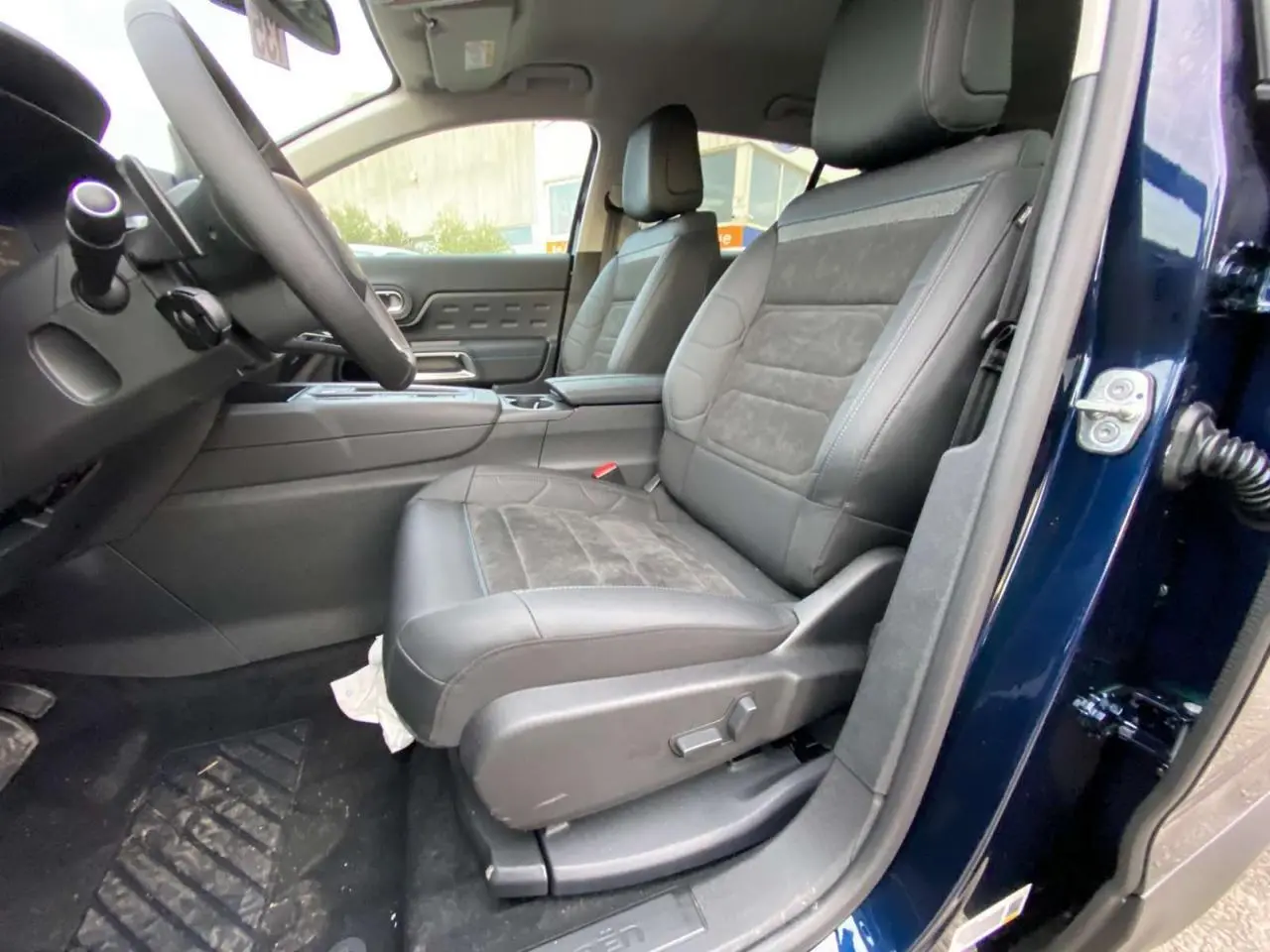 Vue intérieure côté conducteur du Citroën C5 Aircross 2025 bleu Eclipse, sièges en cuir noir avec surpiqûres grises.