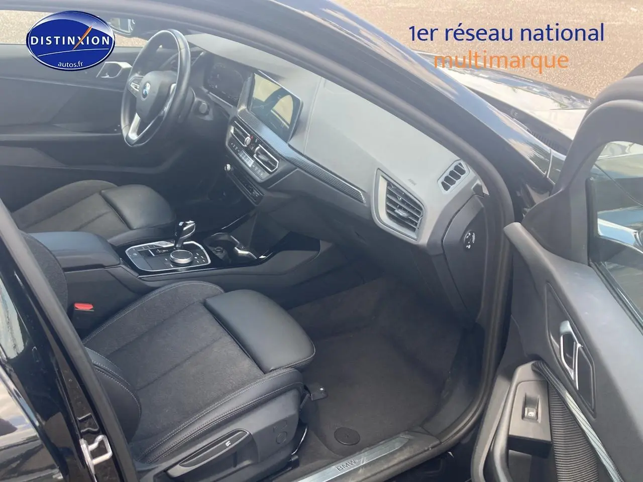 Vue intérieure côté conducteur de la BMW Série 1 noire, montrant sièges sport et tableau de bord moderne.