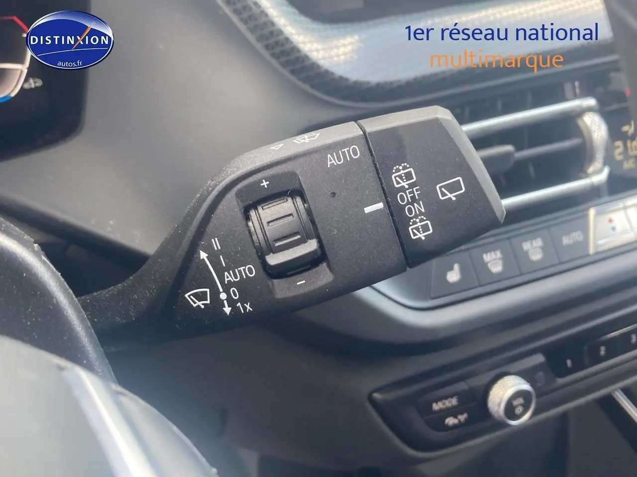 Gros plan sur la commande d’essuie-glace à gauche du volant d’une BMW Série 1 noire, tableau de bord en arrière-plan.