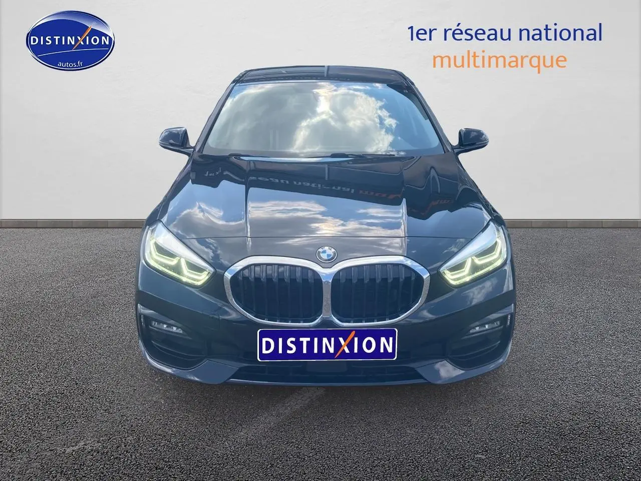 Vue frontale d'une BMW Série 1 noire 2023 avec phares LED allumés et calandre double haricot distinctive.