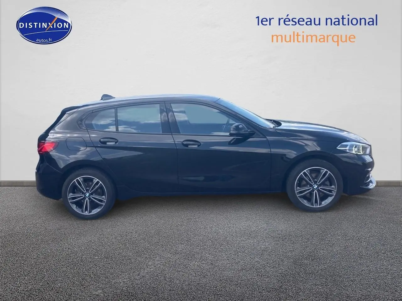 Profil côté gauche d'une BMW Série 1 noire 2023 avec jantes alliage 17 pouces et phares LED allumés.