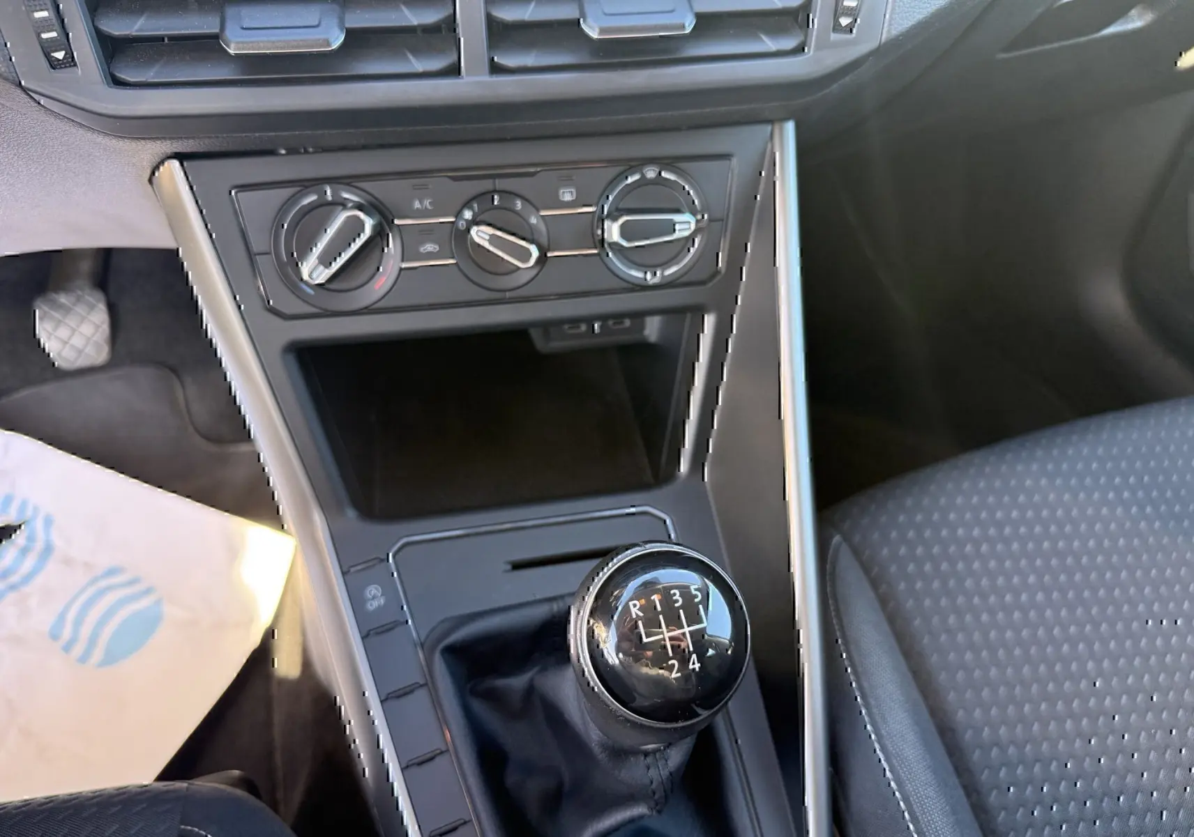 Vue rapprochée de la console centrale grise d’une Volkswagen Polo 2021, mettant en valeur le levier de vitesse manuel et les commandes de climatisation.