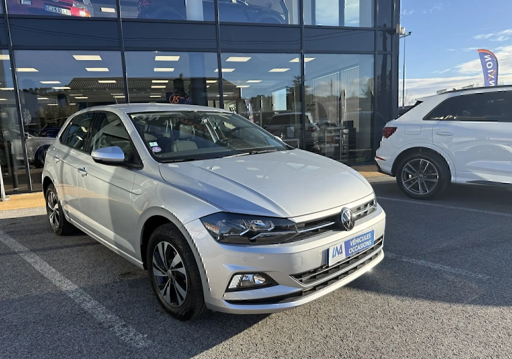 Volkswagen Polo gris métal vue 3/4 avant droit, avec jantes alliage et calandre noire brillante.
