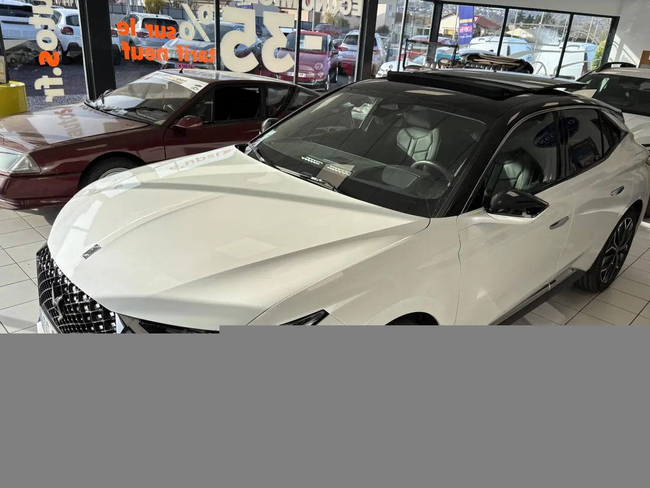 Vue 3/4 avant droite d'une DS4 E-Tense 2023 avec toit noir Perla Nera et carrosserie blanche nacrée en showroom.