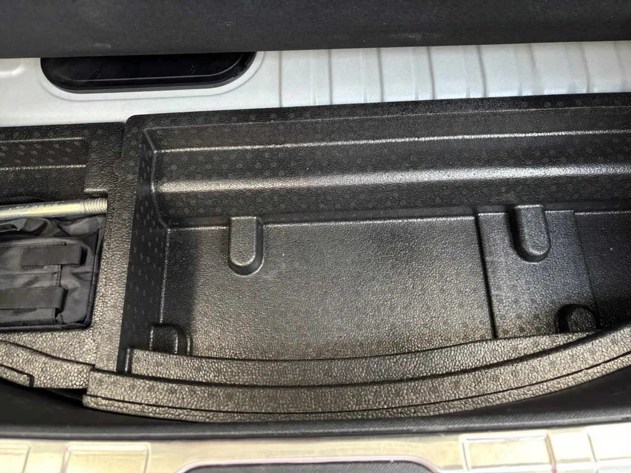 Gros plan sur le compartiment de rangement noir texturé dans le coffre du DS4 E-Tense 2023.