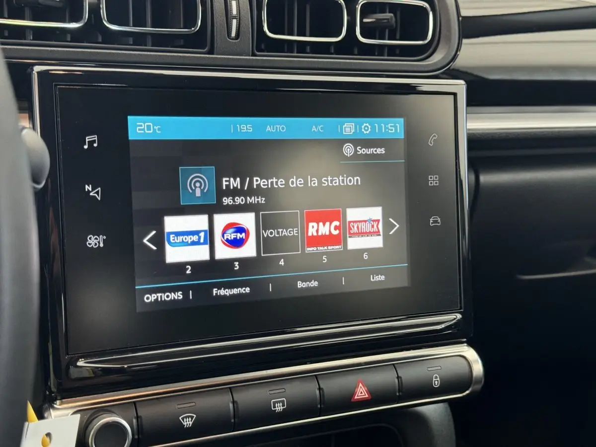 Vue rapprochée de l'écran tactile central du tableau de bord de la Citroën C3 gris foncé, affichant les stations radio FM.