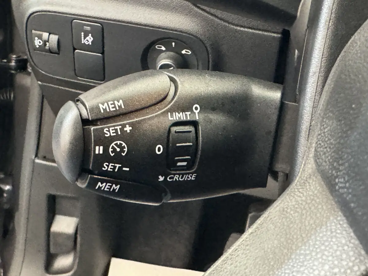 Gros plan sur la commande de régulateur de vitesse côté gauche du volant d'une Citroën C3 gris foncé de 2020.