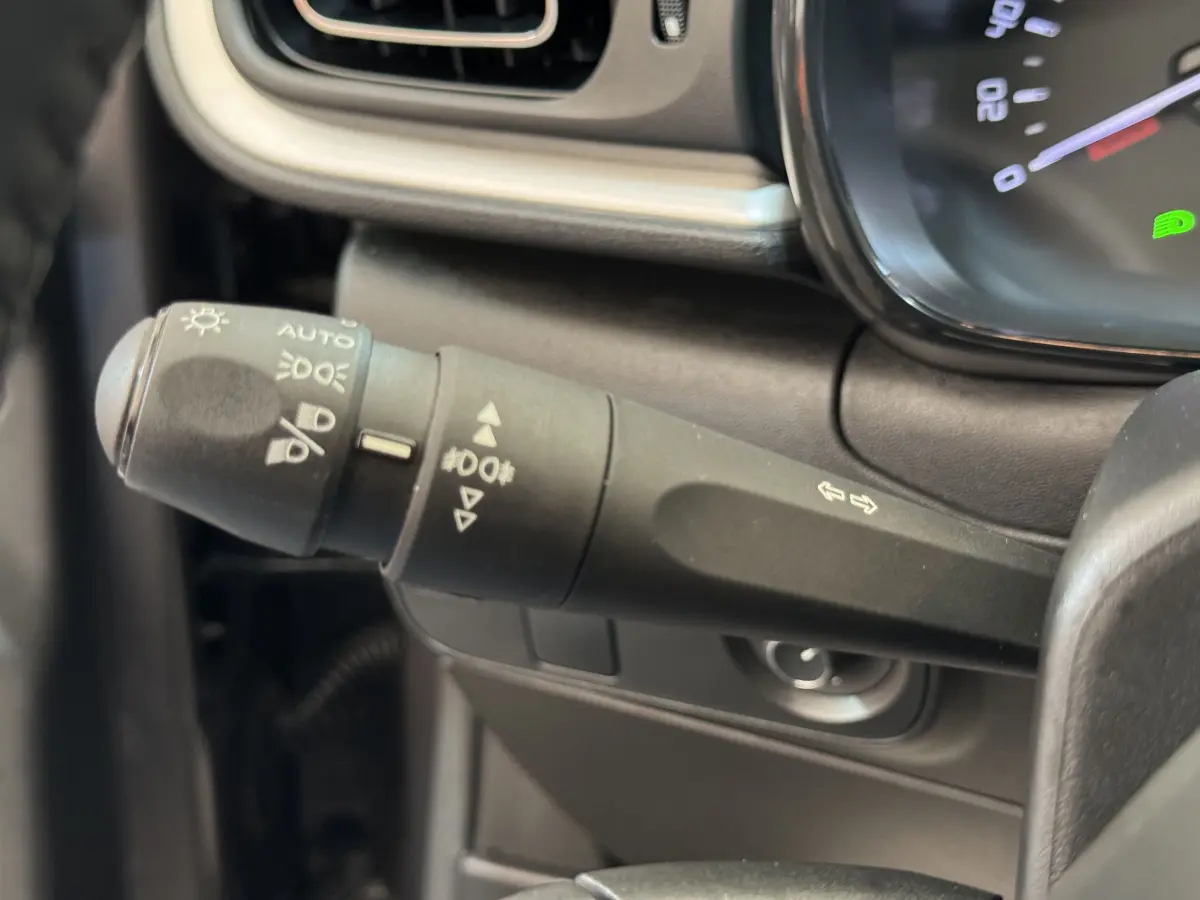 Gros plan sur la manette de commande des phares et clignotants dans l’habitacle d’une Citroën C3 2020 gris foncé.