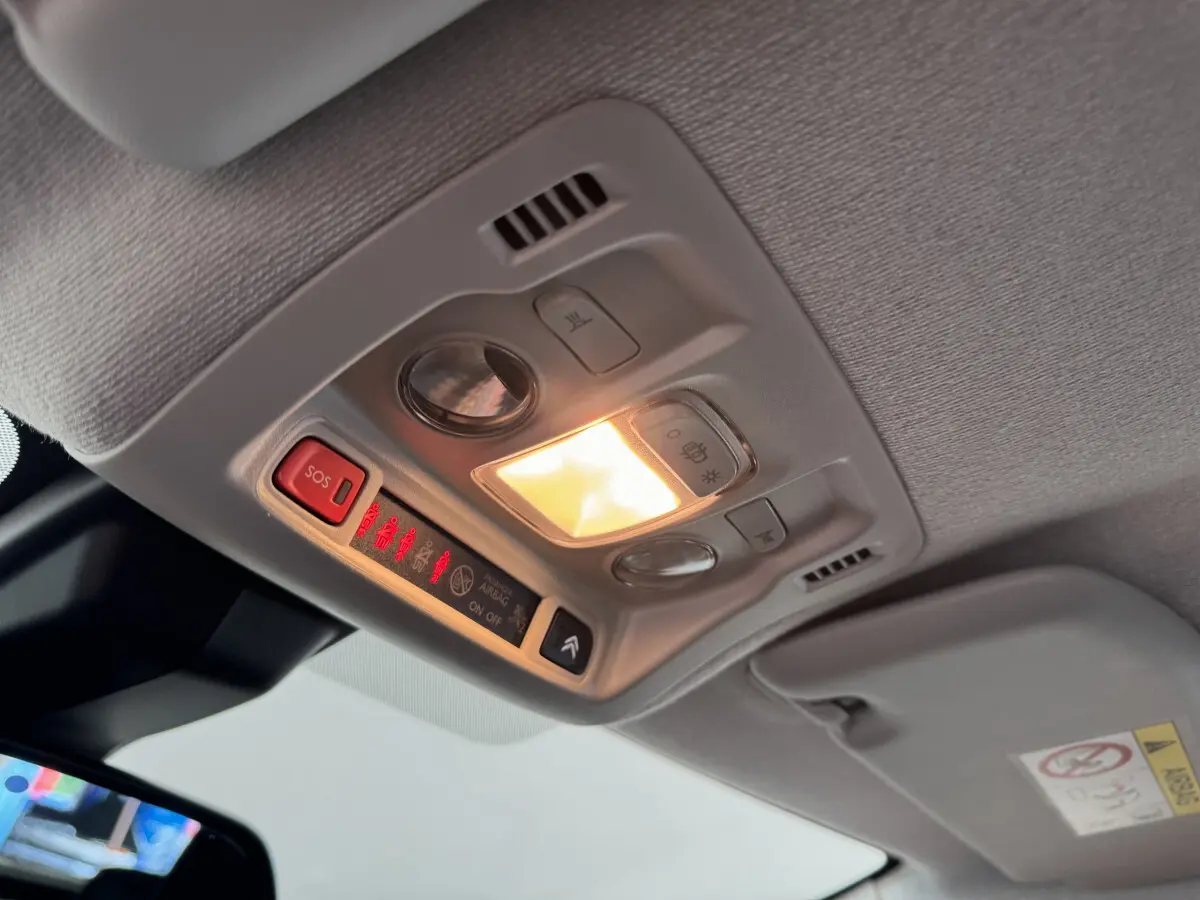 Vue intérieure en contre-plongée du plafonnier gris clair avec éclairage et boutons de commande dans une Citroën C3 gris foncé.