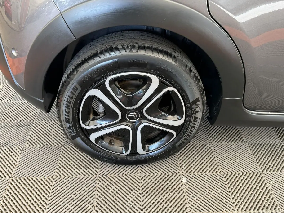 Gros plan sur la roue avant gauche d'une Citroën C3 gris foncé avec jante alliage noire et argentée.