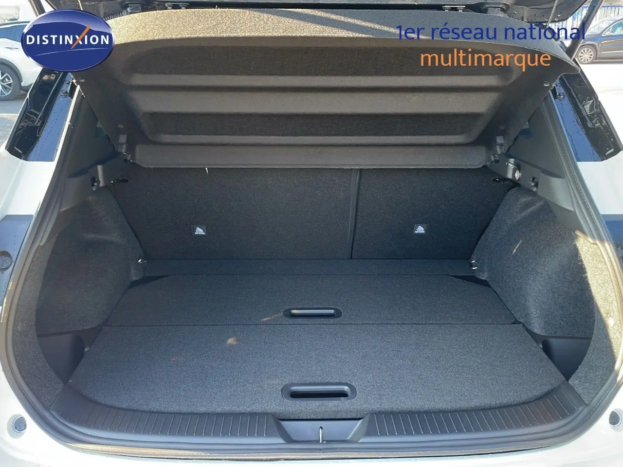 Coffre ouvert d'un Nissan Qashqai blanc nacré avec toit noir, vue arrière montrant un espace de chargement plat et spacieux.