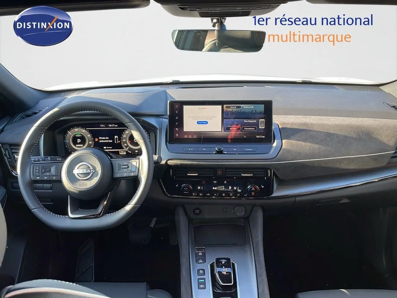 Vue intérieure du tableau de bord du Nissan Qashqai blanc nacré, avec écran tactile et volant multifonction.