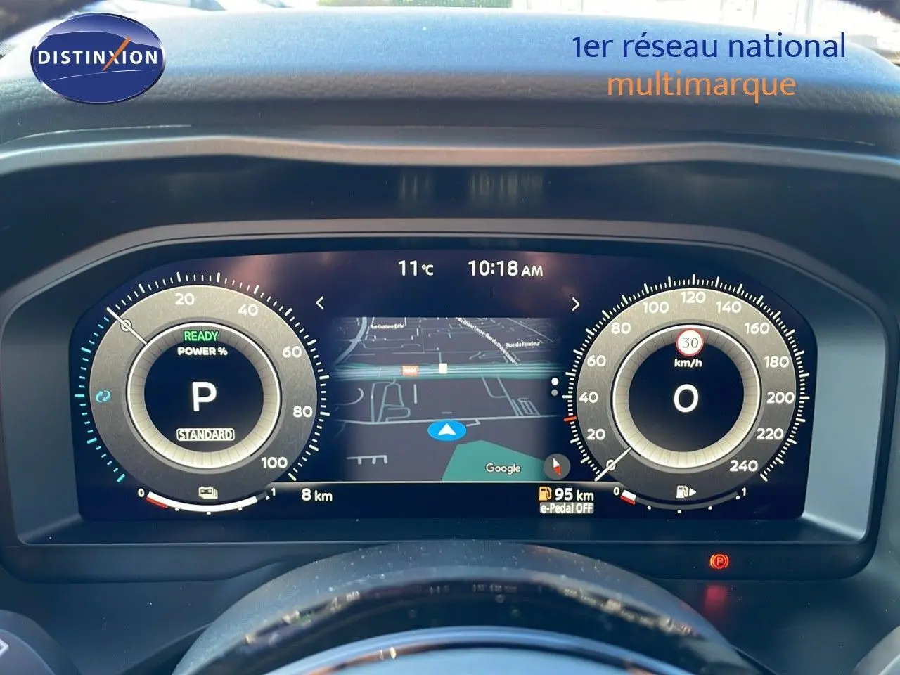 Tableau de bord numérique du Nissan Qashqai blanc nacré, affichant la navigation et les compteurs à 10h18.