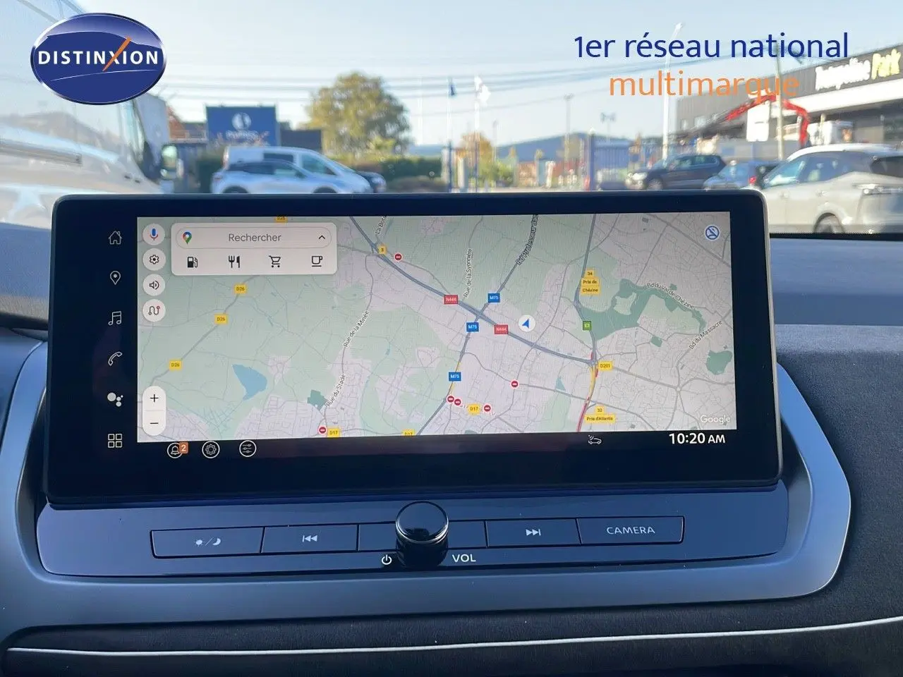 Écran tactile central du Nissan Qashqai blanc nacré, affichant une carte GPS avec commandes multimédia en bas.