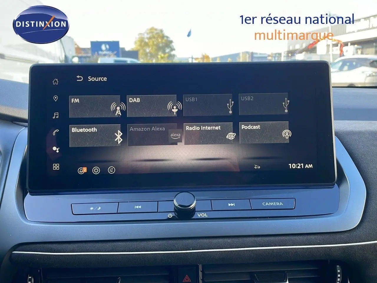 Écran tactile central du Nissan Qashqai blanc nacré avec toit noir, affichant les sources audio et commandes multimédia.