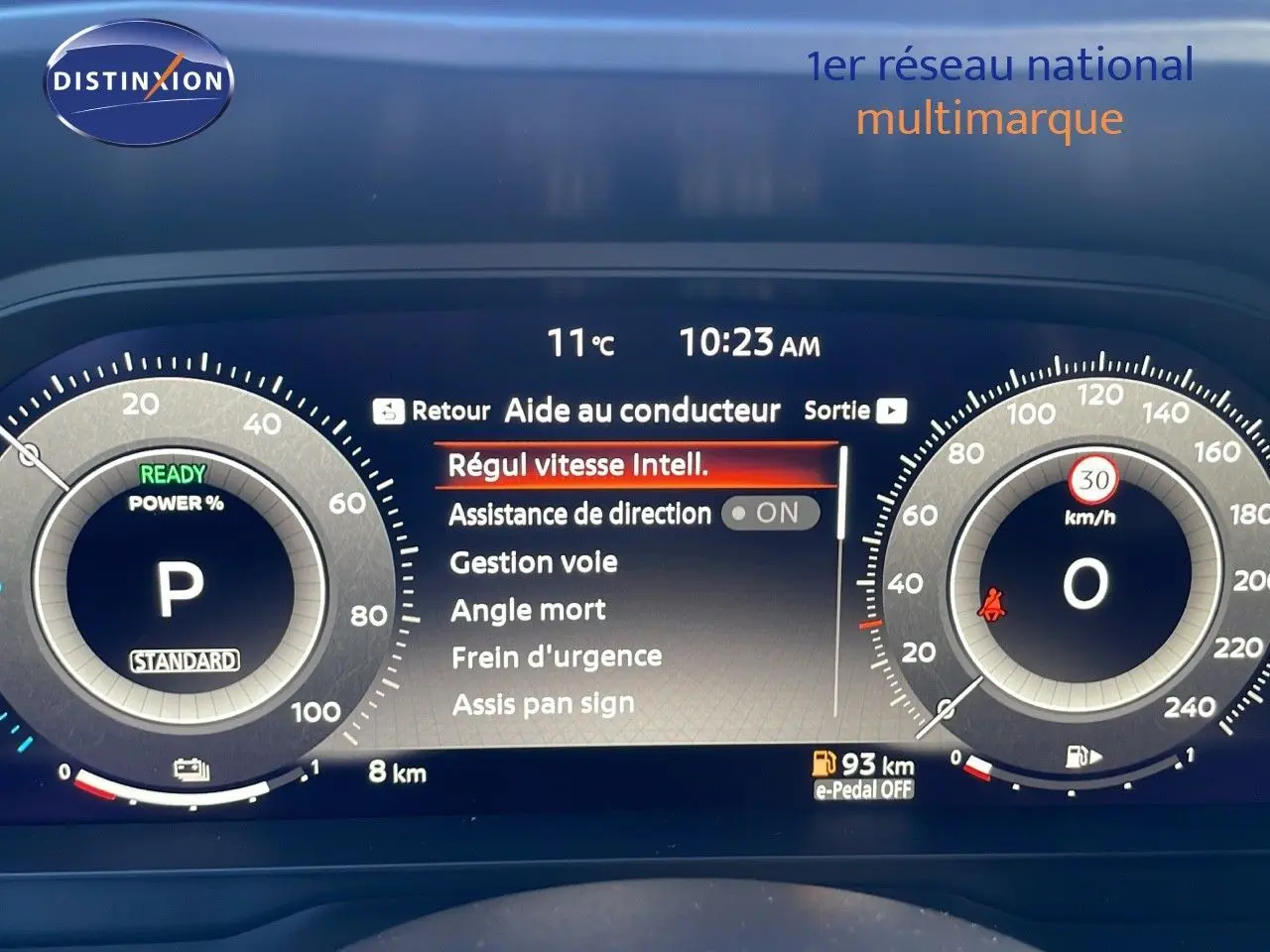 Tableau de bord numérique du Nissan Qashqai blanc nacré, affichant l'aide au conducteur et la vitesse à 0 km/h.