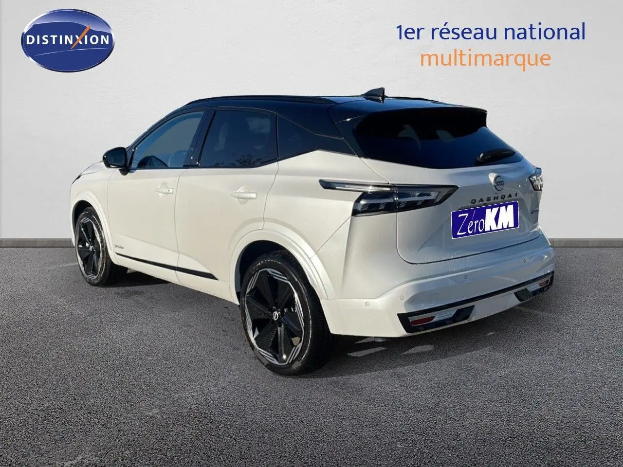 Vue 3/4 arrière droite du Nissan Qashqai blanc nacré avec toit noir, jantes noires et feux arrière LED modernes.