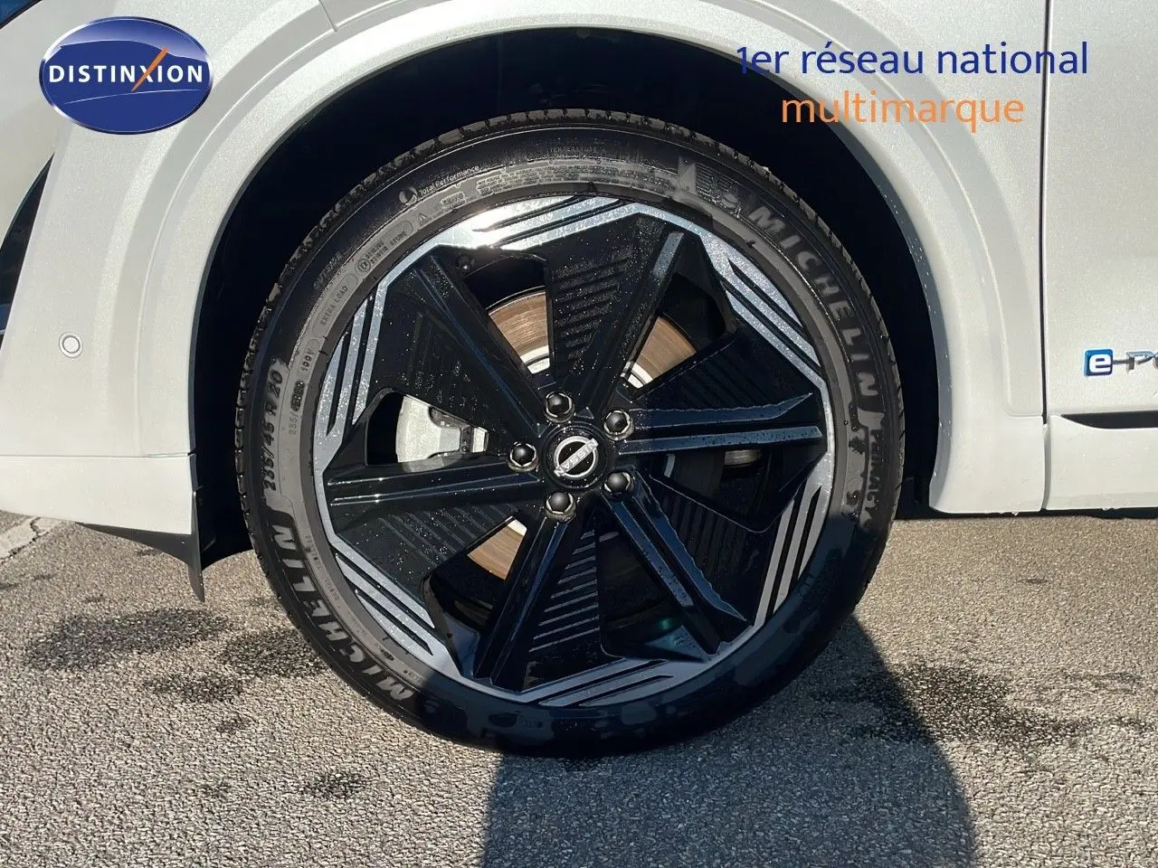 Gros plan sur la roue avant gauche du Nissan Qashqai blanc nacré avec jante noire et détails gris métallisé.