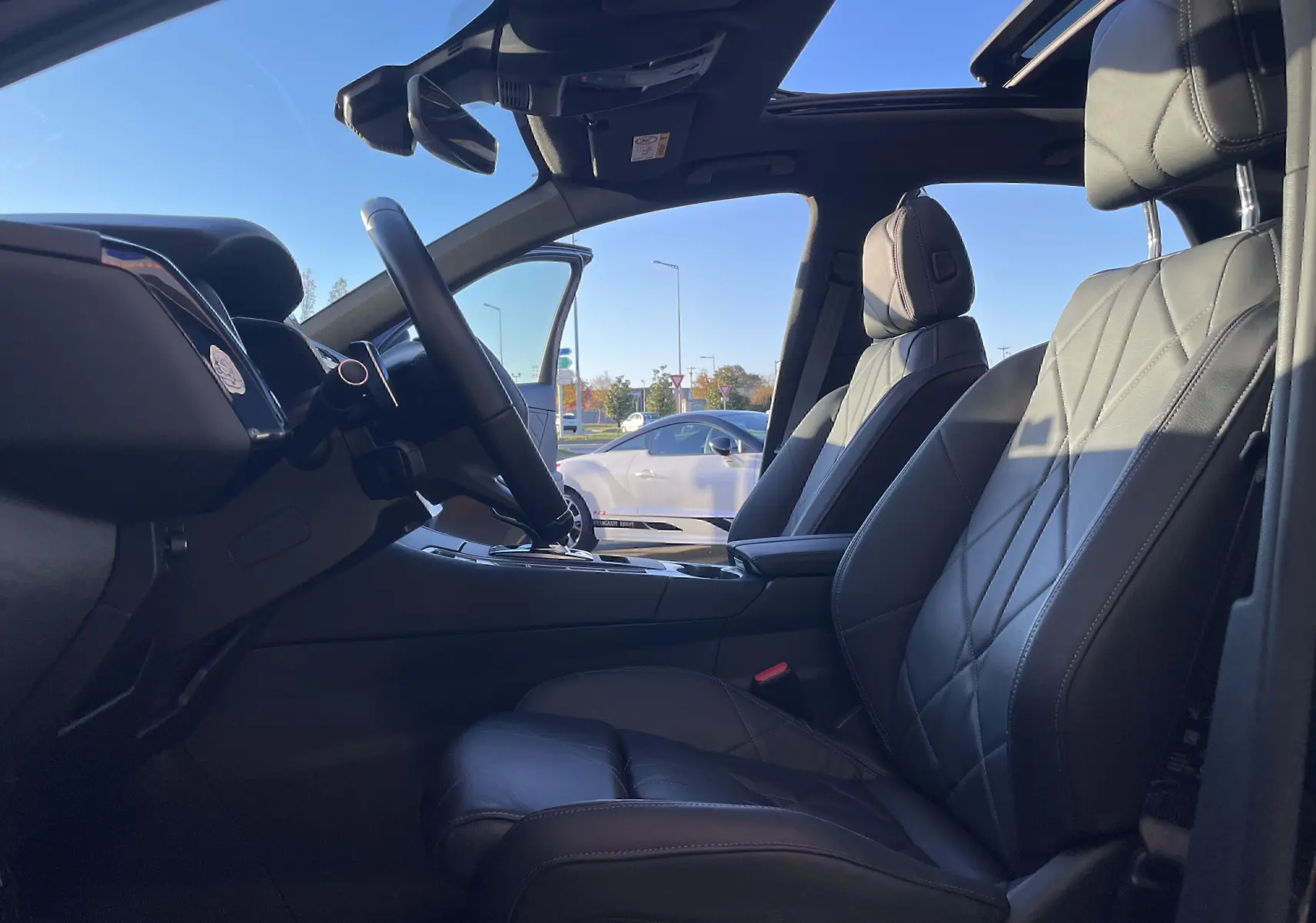 Intérieur du DS7 2024 en cuir noir, vue latérale côté conducteur avec toit ouvrant et tableau de bord visible.