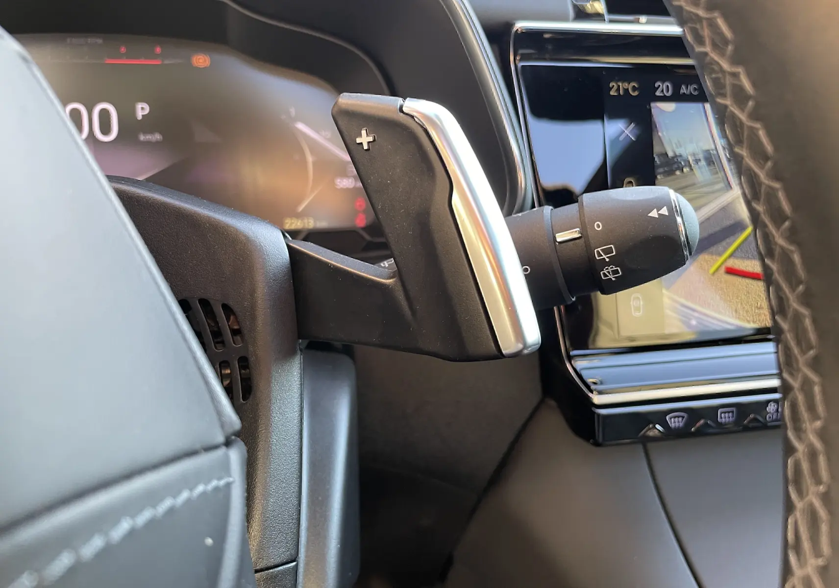 Gros plan sur la palette de changement de vitesse droite et le tableau de bord numérique du DS7 noir Perla Nera 2024.