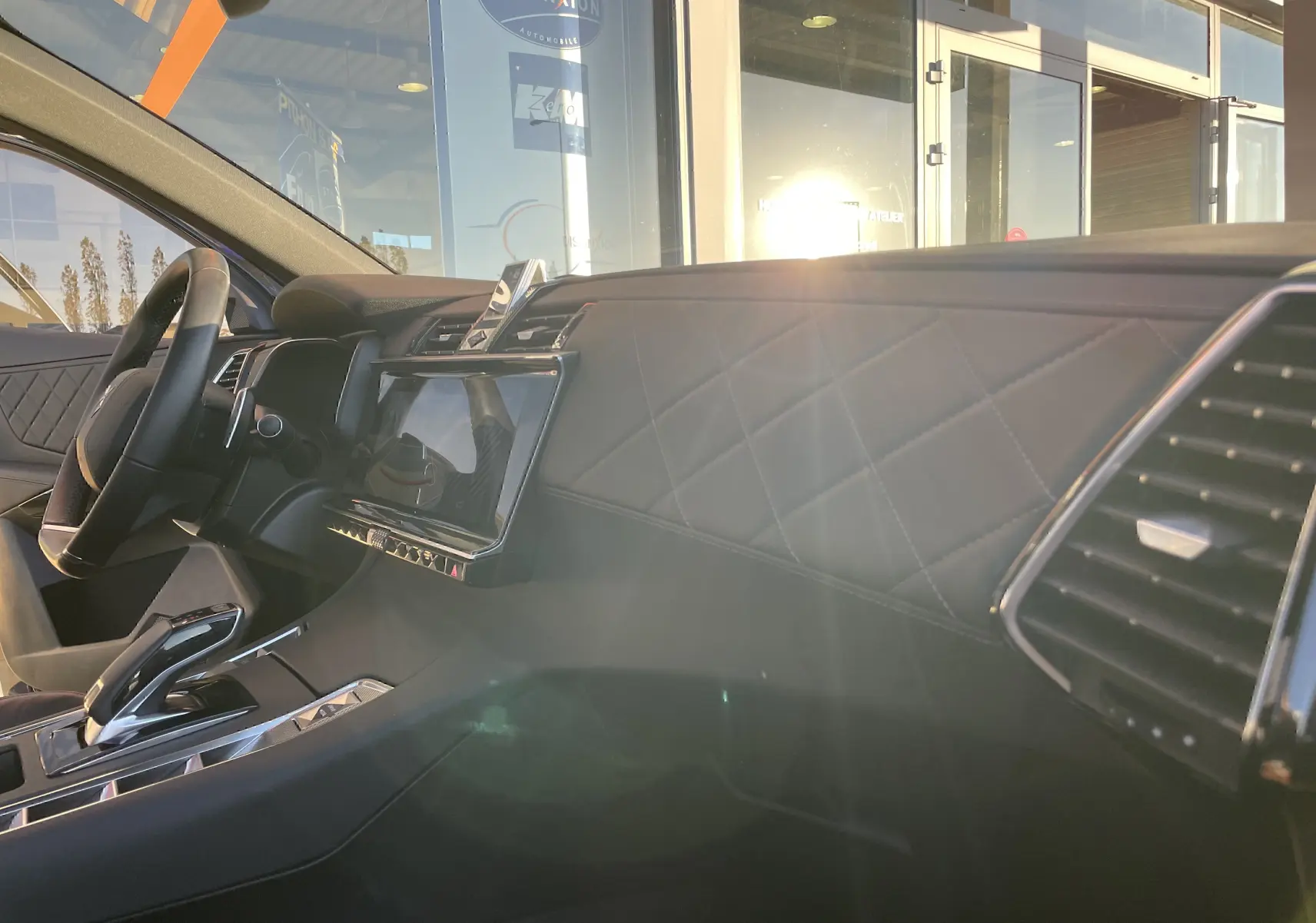 Intérieur côté passager du DS7 2024 noir Perla Nera, tableau de bord en cuir noir matelassé avec écran tactile central.