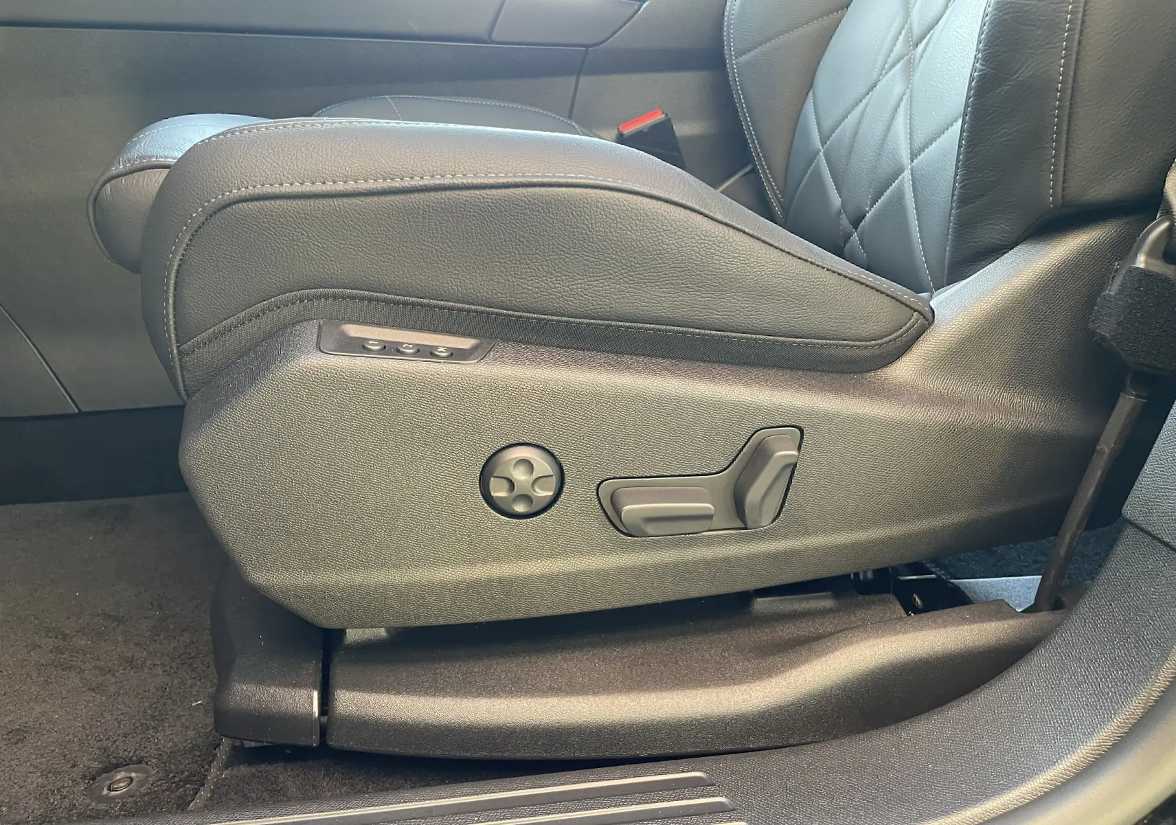 Gros plan sur les commandes de réglage électrique du siège avant gauche en cuir noir du DS7 2024.