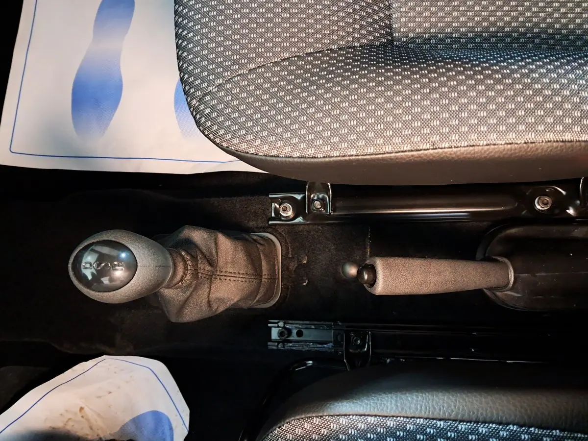 Gros plan intérieur montrant levier de boîte automatique et frein à main entre sièges tissu gris d'une Aixam Minauto E chic 2025.