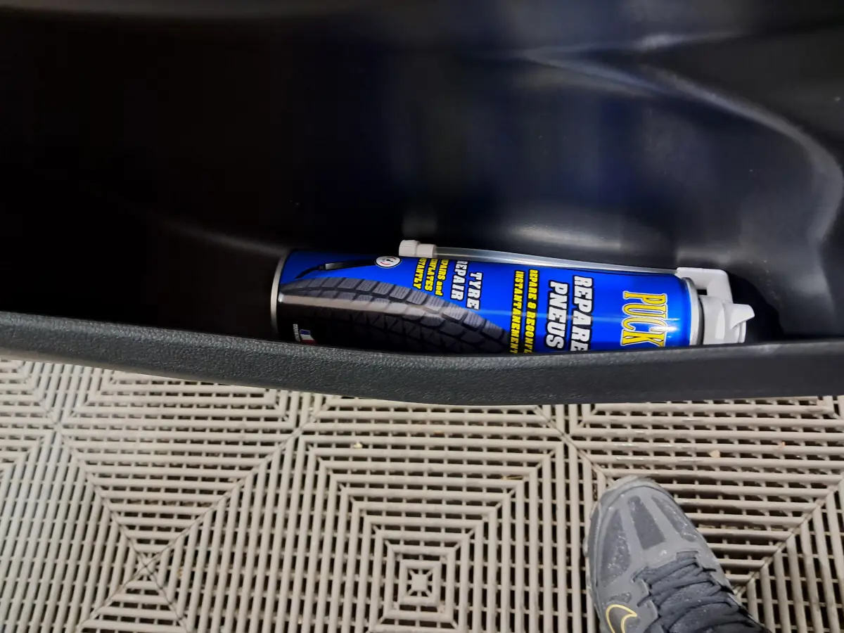 Vue intérieure du coffre d'une Aixam Minauto E chic 2025, avec bombe de réparation pneus visible et sol en plastique.