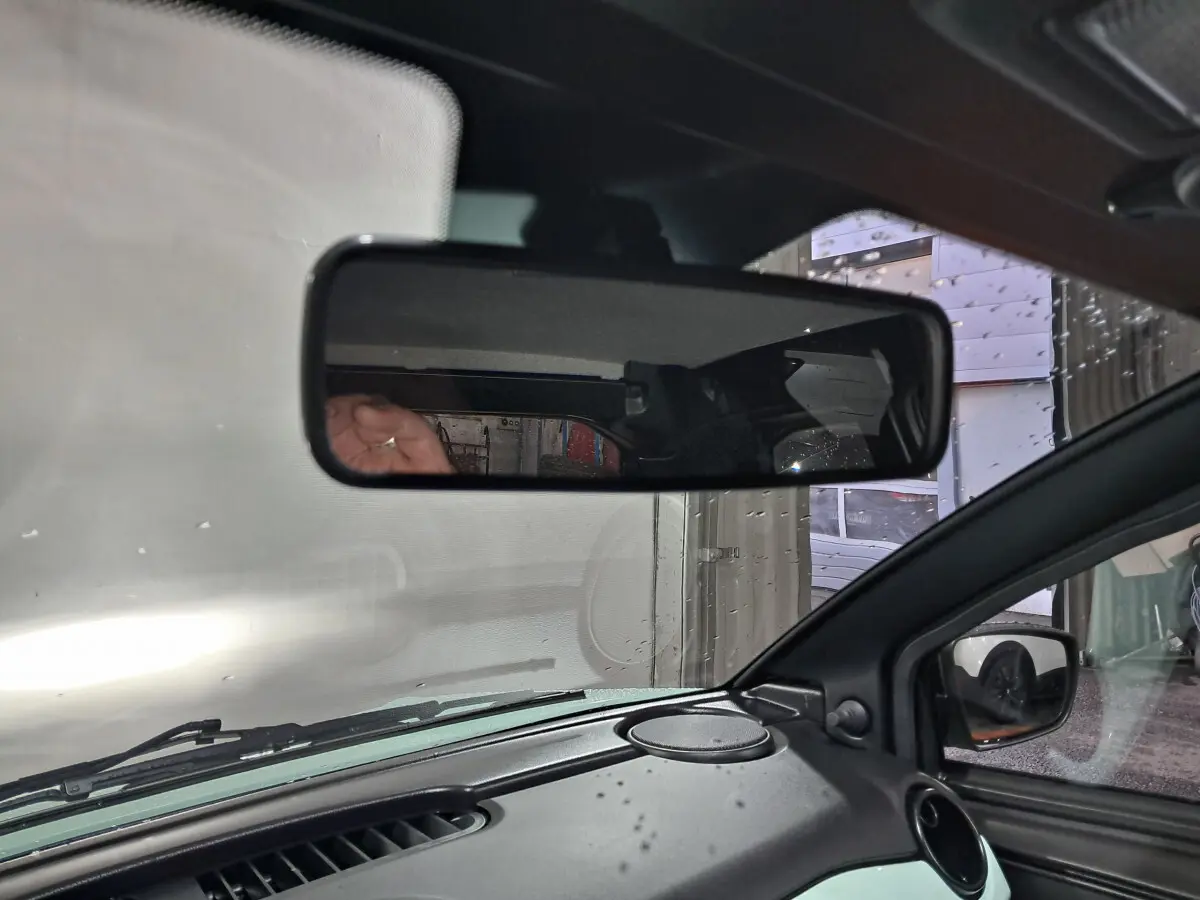 Vue intérieure du rétroviseur central et du tableau de bord d'une Aixam Minauto E chic 2025 en vert électrique.