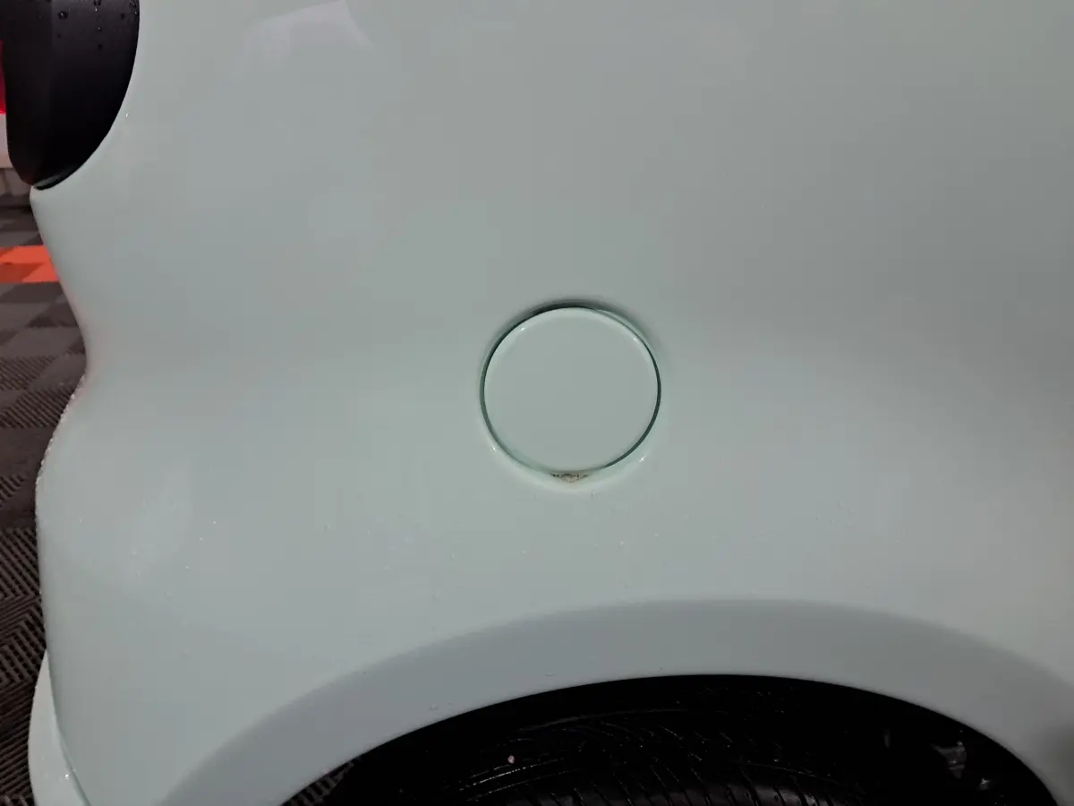 Gros plan sur la trappe de carburant côté gauche d'une Aixam Minauto E chic 2025 vert électrique.