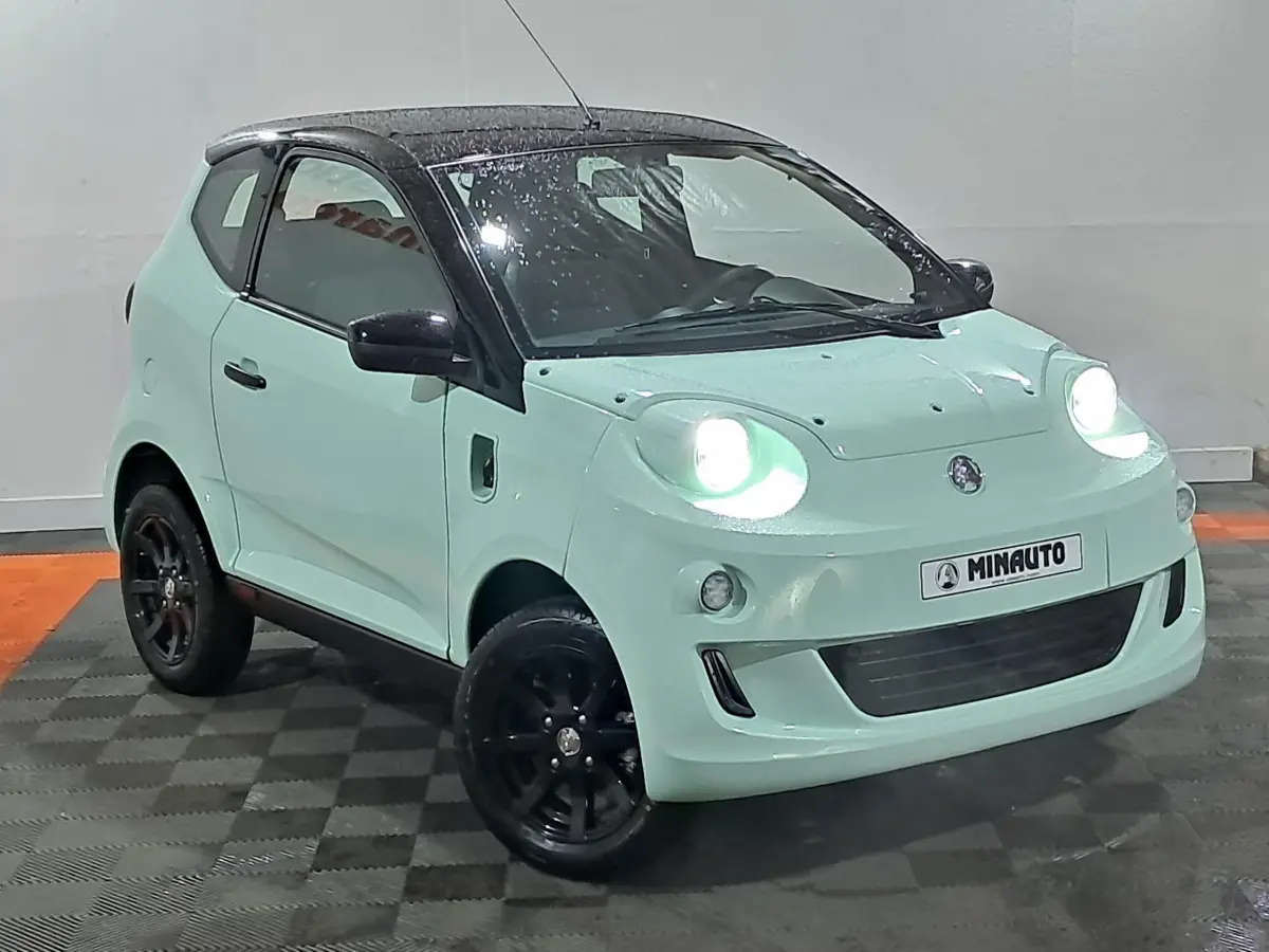 Vue 3/4 avant d'une AIXAM MINAUTO E chic électrique 2025 vert clair avec toit noir et jantes noires.