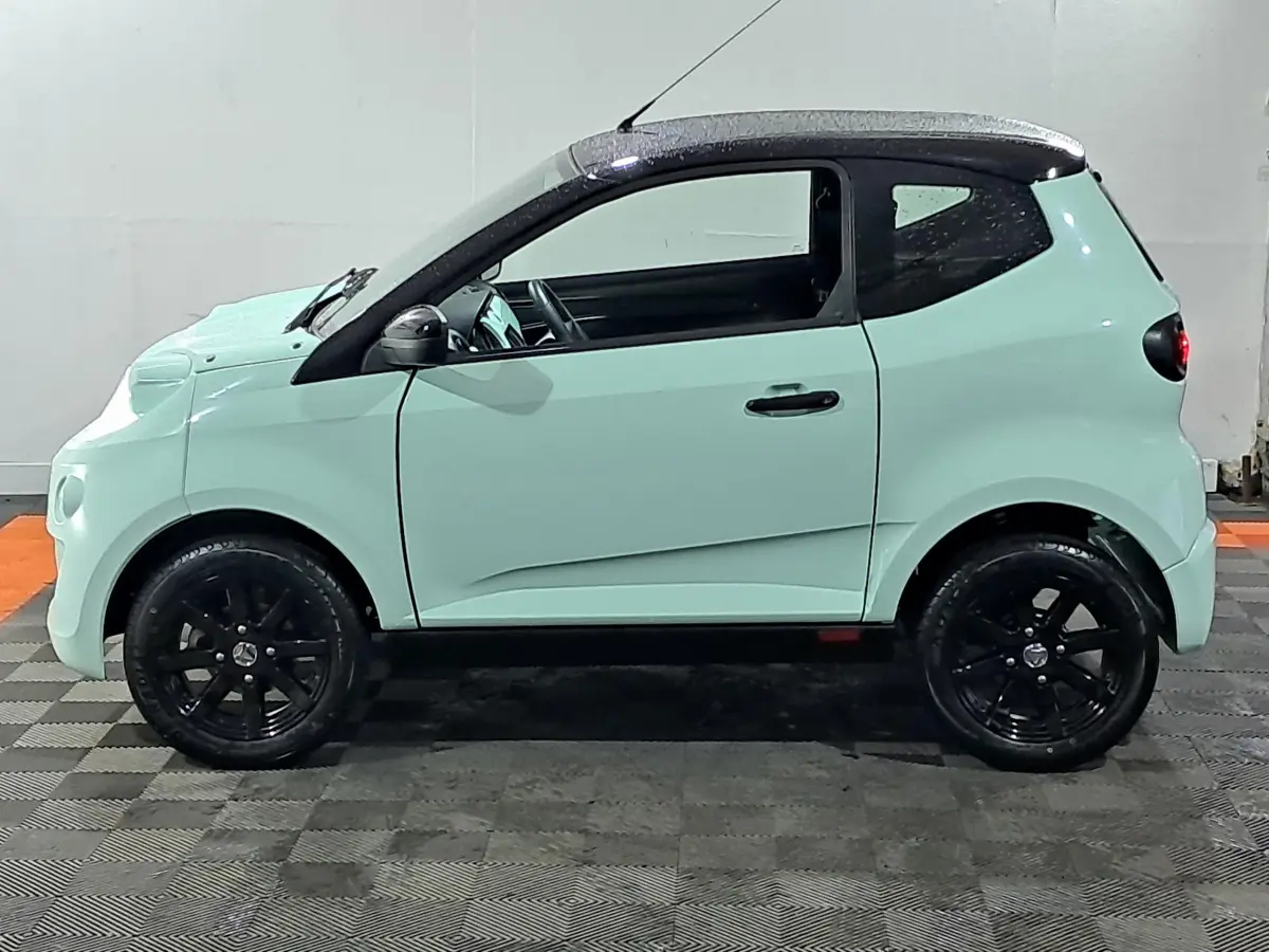 Profil côté gauche d'une AIXAM MINAUTO E chic 2025 électrique vert clair avec toit noir et jantes noires.