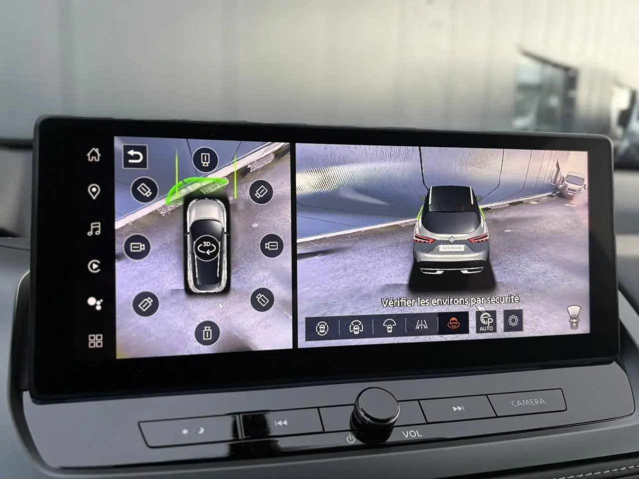 Écran intérieur affichant la vue 360° d'un Nissan Qashqai gris Ceramic en stationnement, vue arrière et dessus.