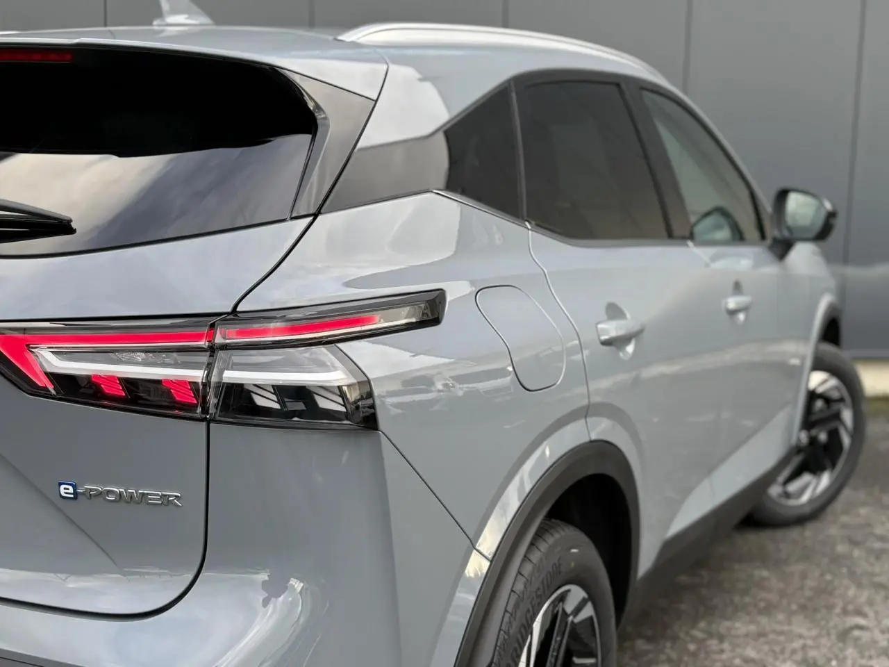 Vue 3/4 arrière droite du Nissan Qashqai gris Ceramic avec feux arrière LED et badge e-POWER visible.