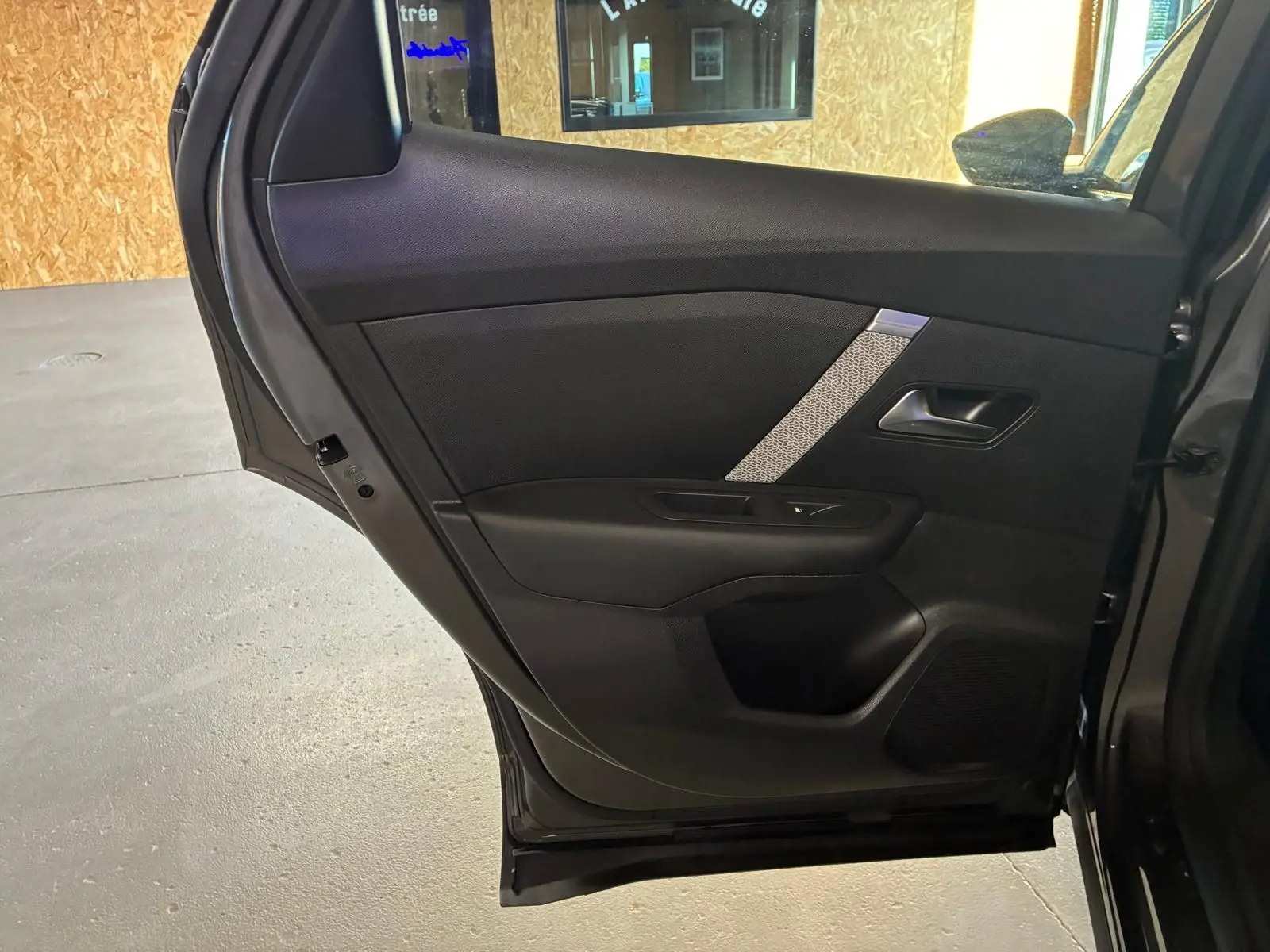 Vue rapprochée de la porte arrière droite grise du Citroën C4 X 2024, avec garniture noire et insert décoratif argenté.