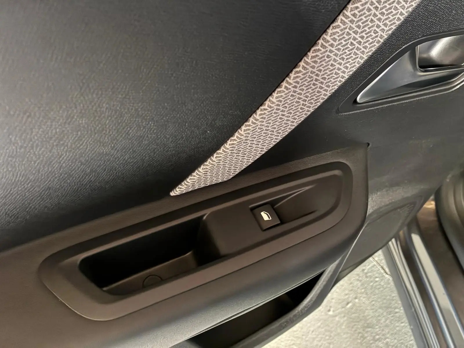 Gros plan sur la commande de lève-vitre côté gauche de la porte intérieure d’une Citroën C4 X gris 2024.