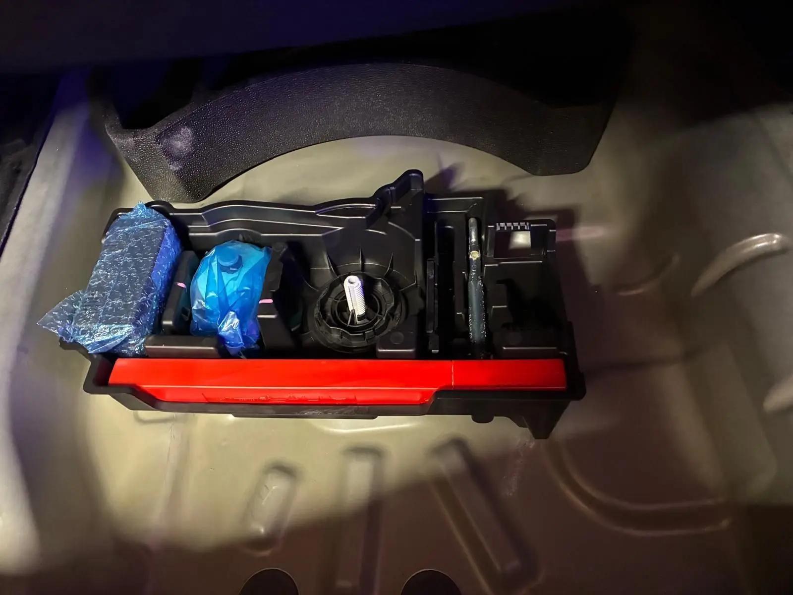 Rangement d’outils dans le coffre d’une Citroën C4 X gris, vue plongeante sur les accessoires bien rangés.