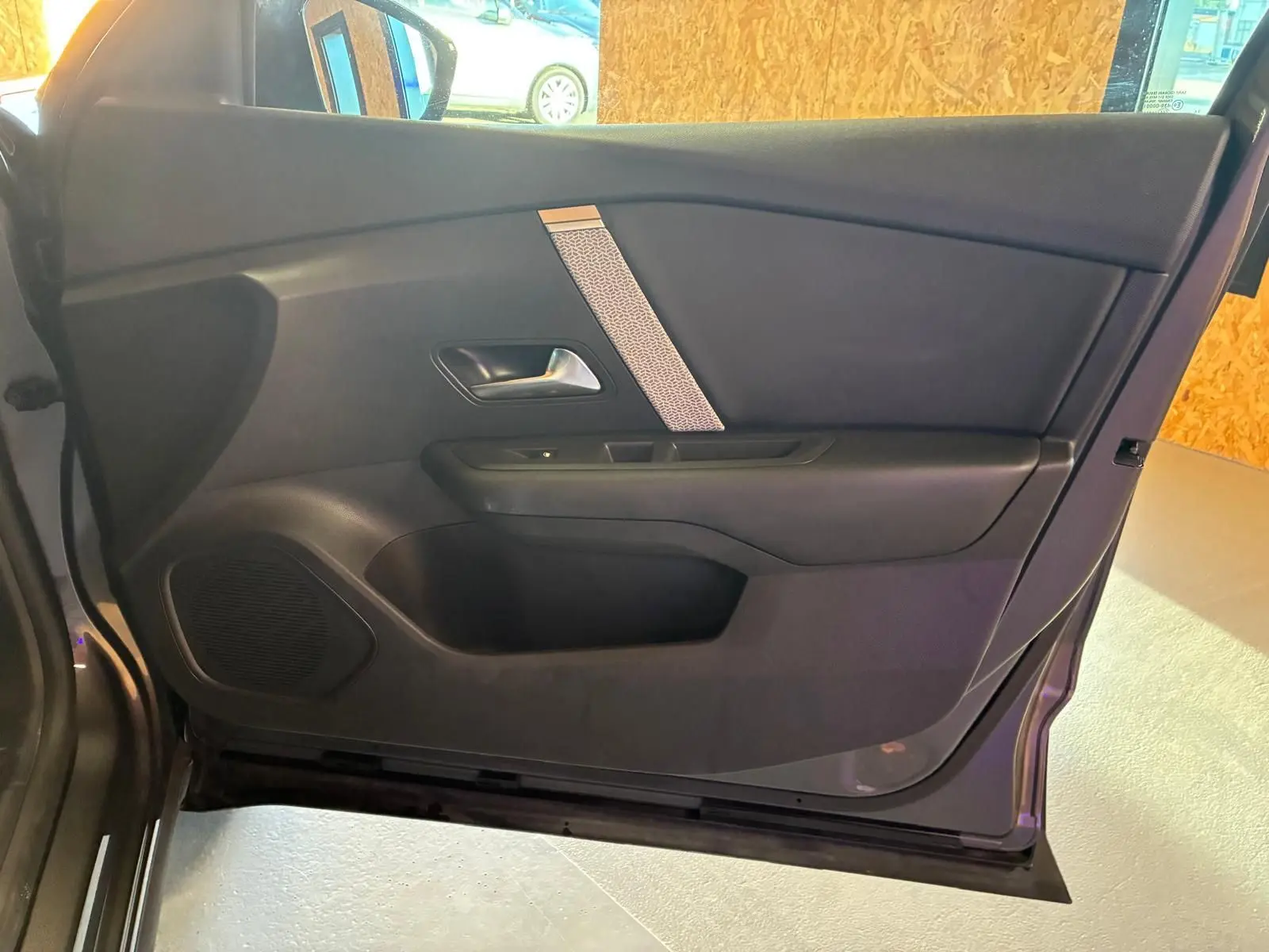 Vue intérieure de la porte côté gauche de la Citroën C4 X gris, avec poignée argentée et haut-parleur intégré.