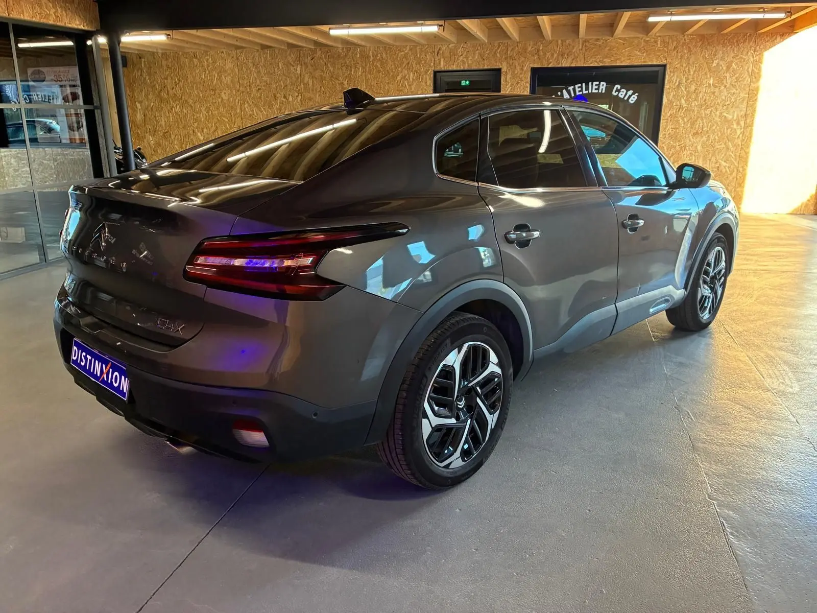 Vue 3/4 arrière droite d'une Citroën C4 X gris métallisé 2024 avec feux arrière LED et jantes alliage distinctives.
