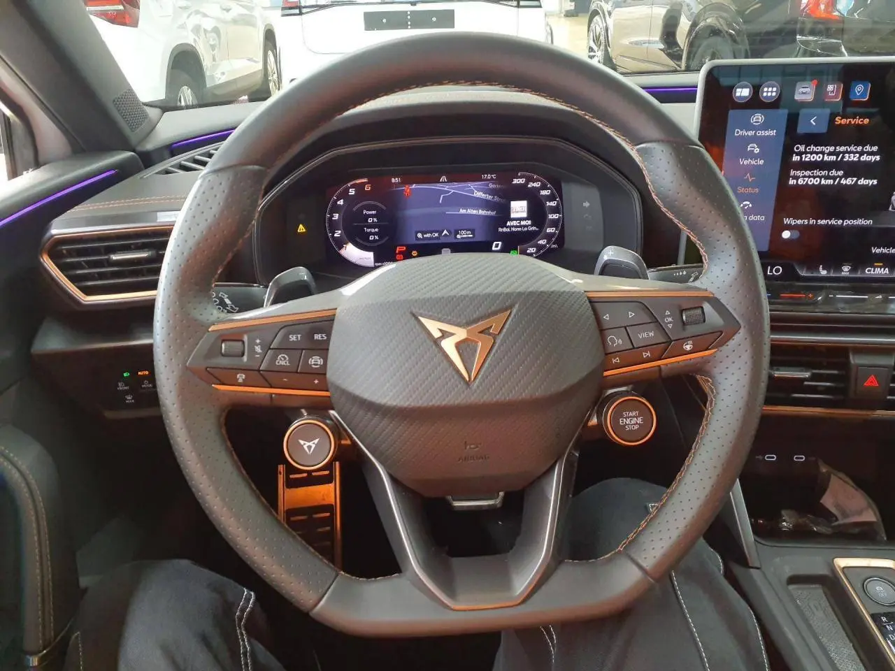 Vue intérieure centrée sur le volant cuir perforé CUPRA avec tableau de bord digital et écran tactile à droite.