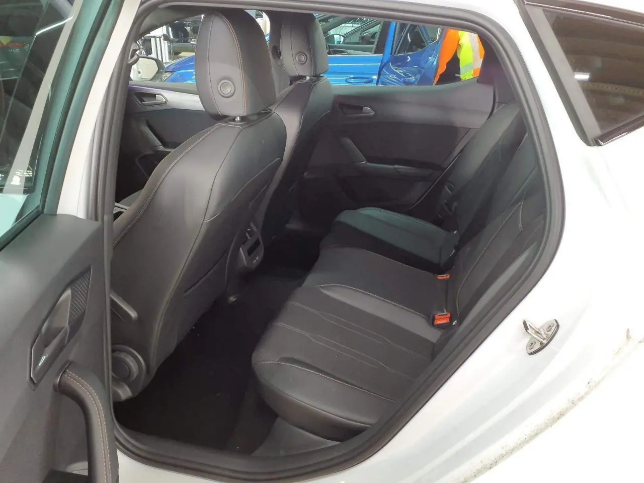 Vue intérieure côté arrière droit de la CUPRA Leon blanche Nevada, montrant les sièges arrière en cuir noir avec surpiqûres contrastées.