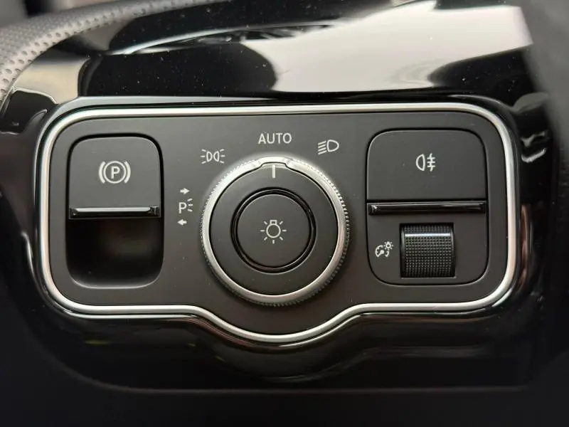 Gros plan sur la commande des feux et du frein de stationnement dans l'habitacle noir brillant d'une Mercedes Classe A 200 d AMG Line.