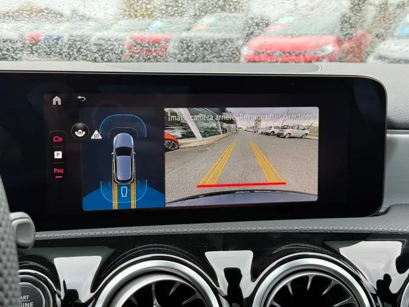 Écran tactile intérieur montrant la caméra de recul et l’aide au stationnement du Mercedes Classe A gris montagne métallisé.