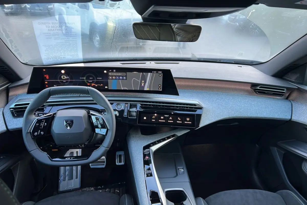 Vue intérieure du Peugeot 3008 Hybrid 145 GT Alcantara 2025, tableau de bord moderne avec écran large et volant compact cuir noir.