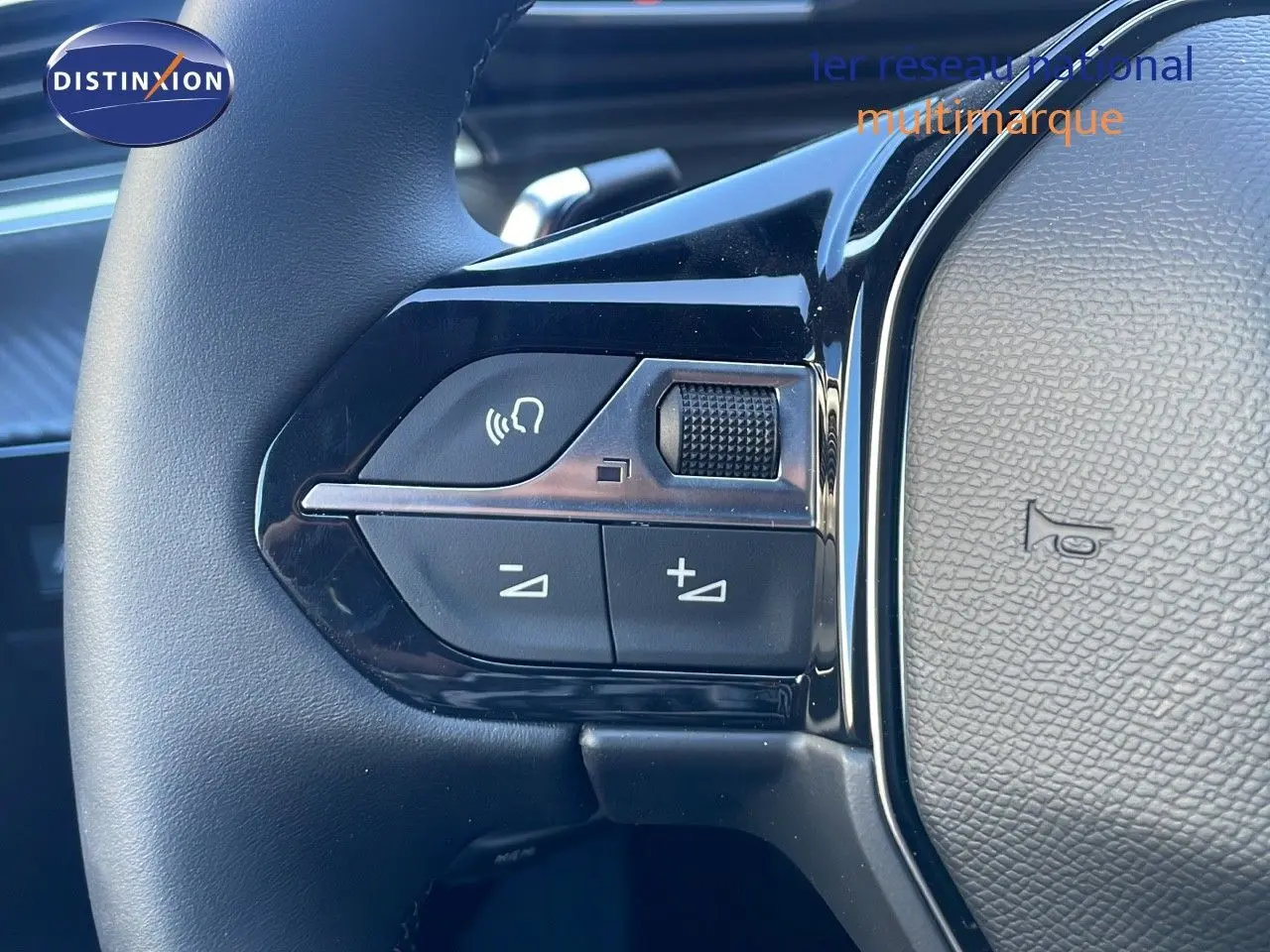 Gros plan sur les commandes gauche du volant en cuir noir de la Peugeot 508 SW 2024 finition Allure.