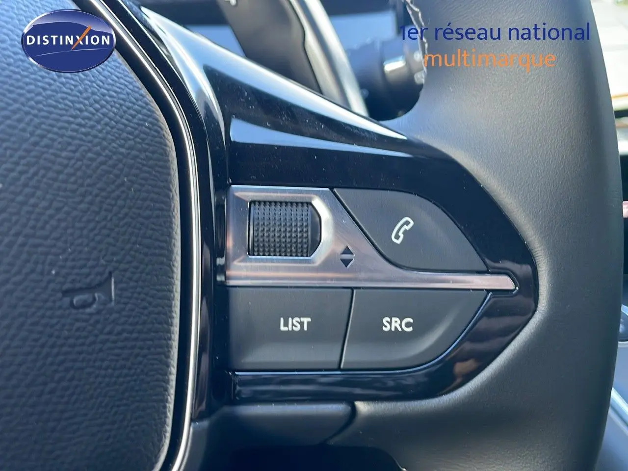 Gros plan sur les commandes du volant noir de la Peugeot 508 SW 2024, avec boutons list et appel.