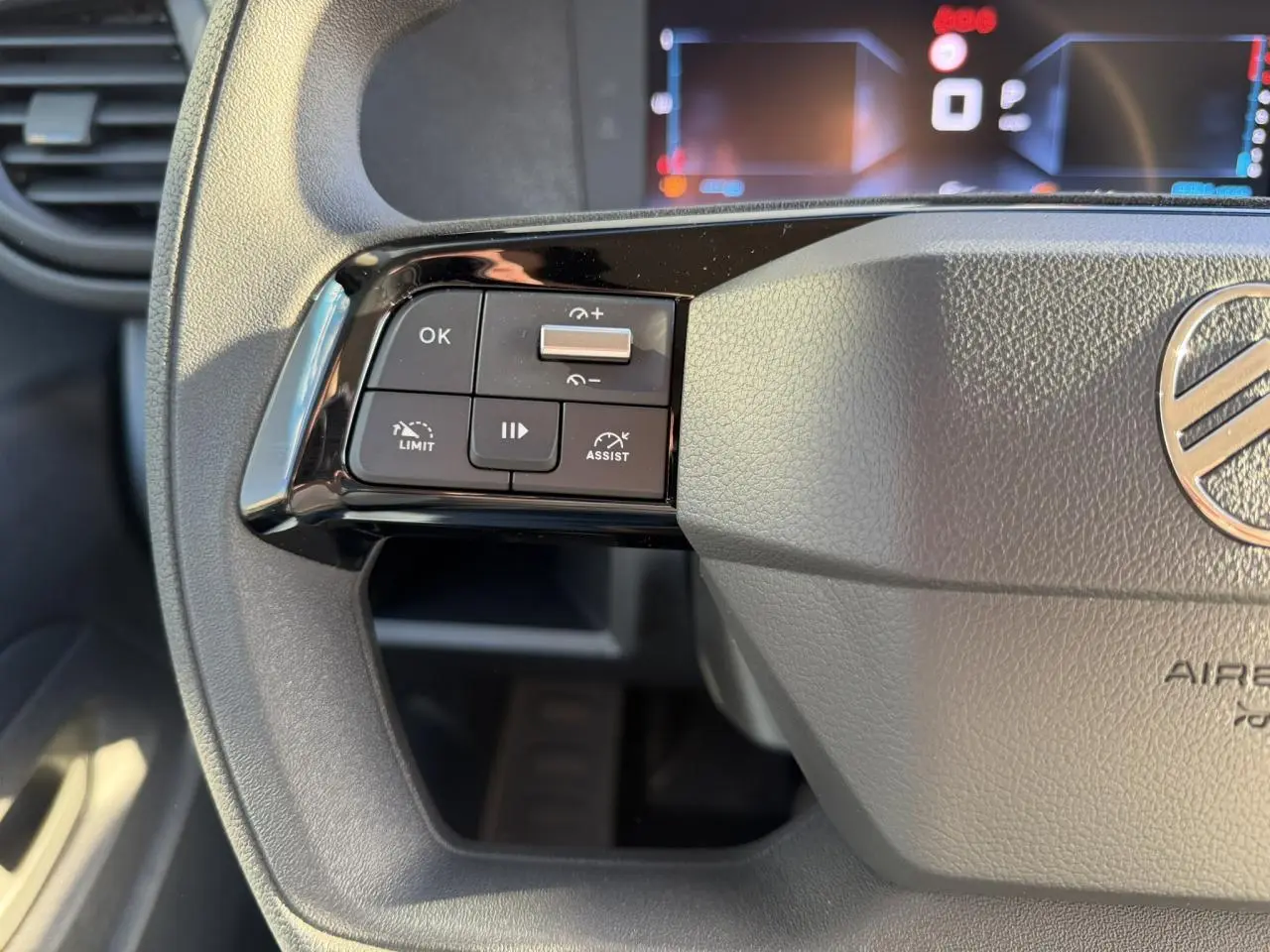 Gros plan sur les commandes à gauche du volant gris du Citroën Jumpy XL 2025 avec écran numérique en arrière-plan.