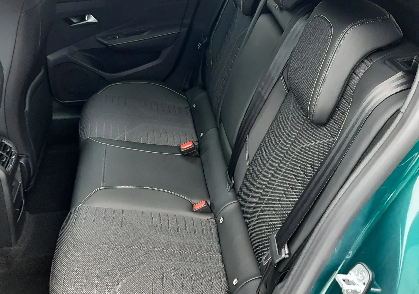 Vue intérieure côté droit sur la banquette arrière noire avec surpiqûres, porte ouverte d'une Peugeot 308 Bleu Lagoa.