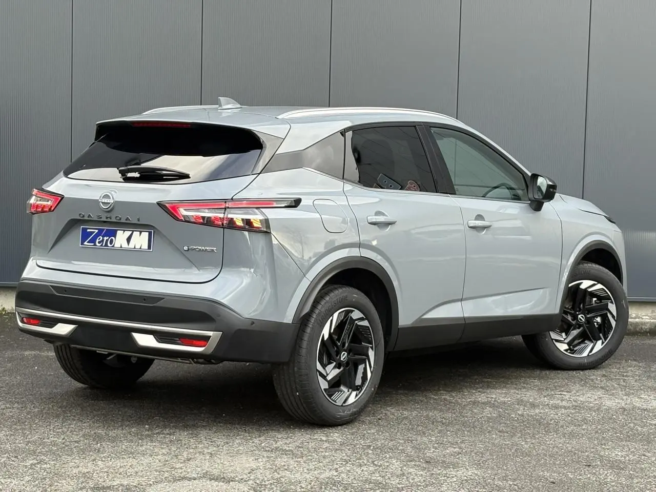 Nissan Qashqai 2025 gris Ceramic en 3/4 arrière droit, avec jantes alliage noires et feux LED distinctifs.